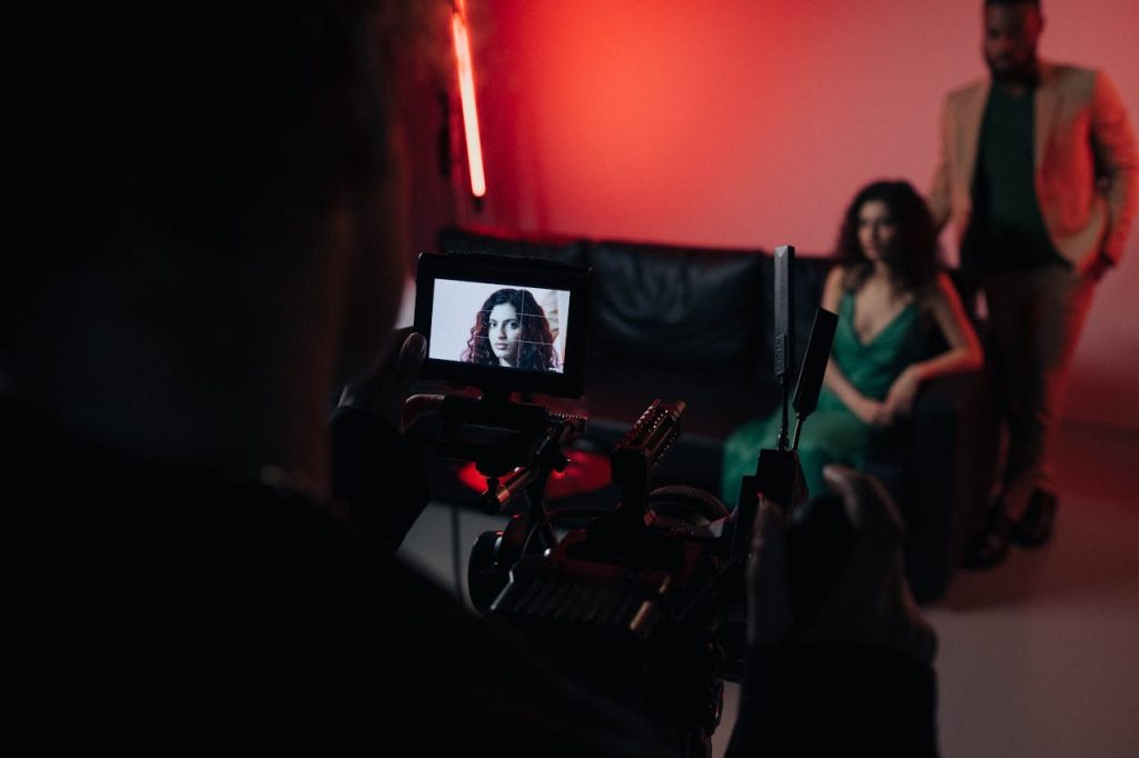 person-filming-the-scene-8089657 Behind the scenes of a studio filming session focused on actors within a creative setup.